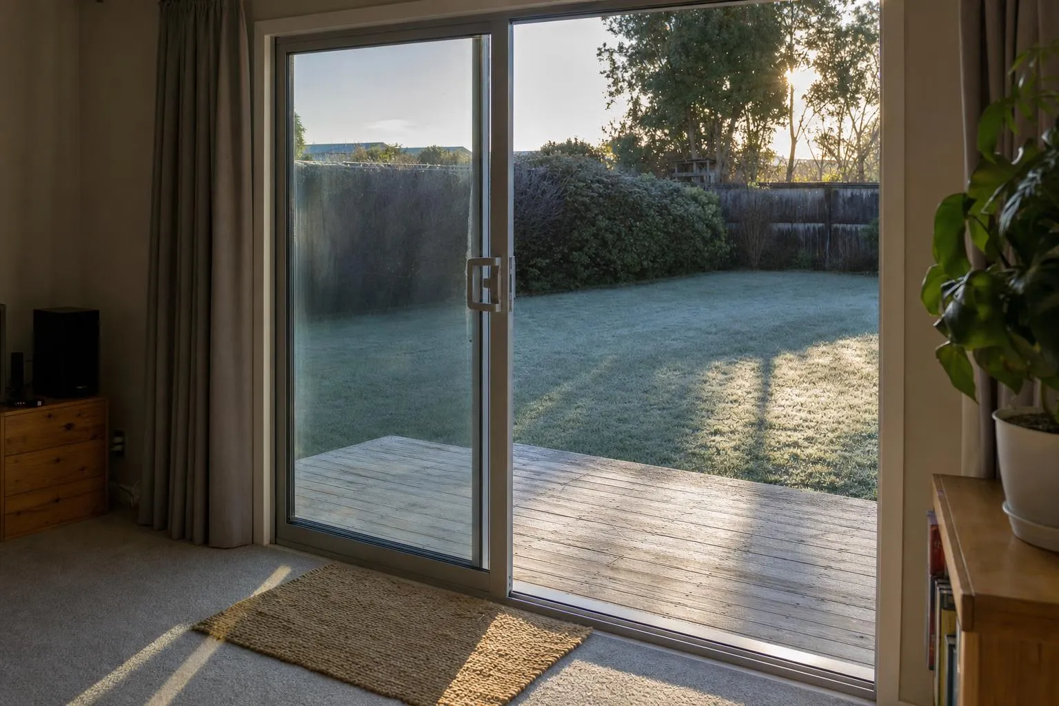 Illustrative: an aluminium ranch slider half open onto a small deck and a frosty lawn