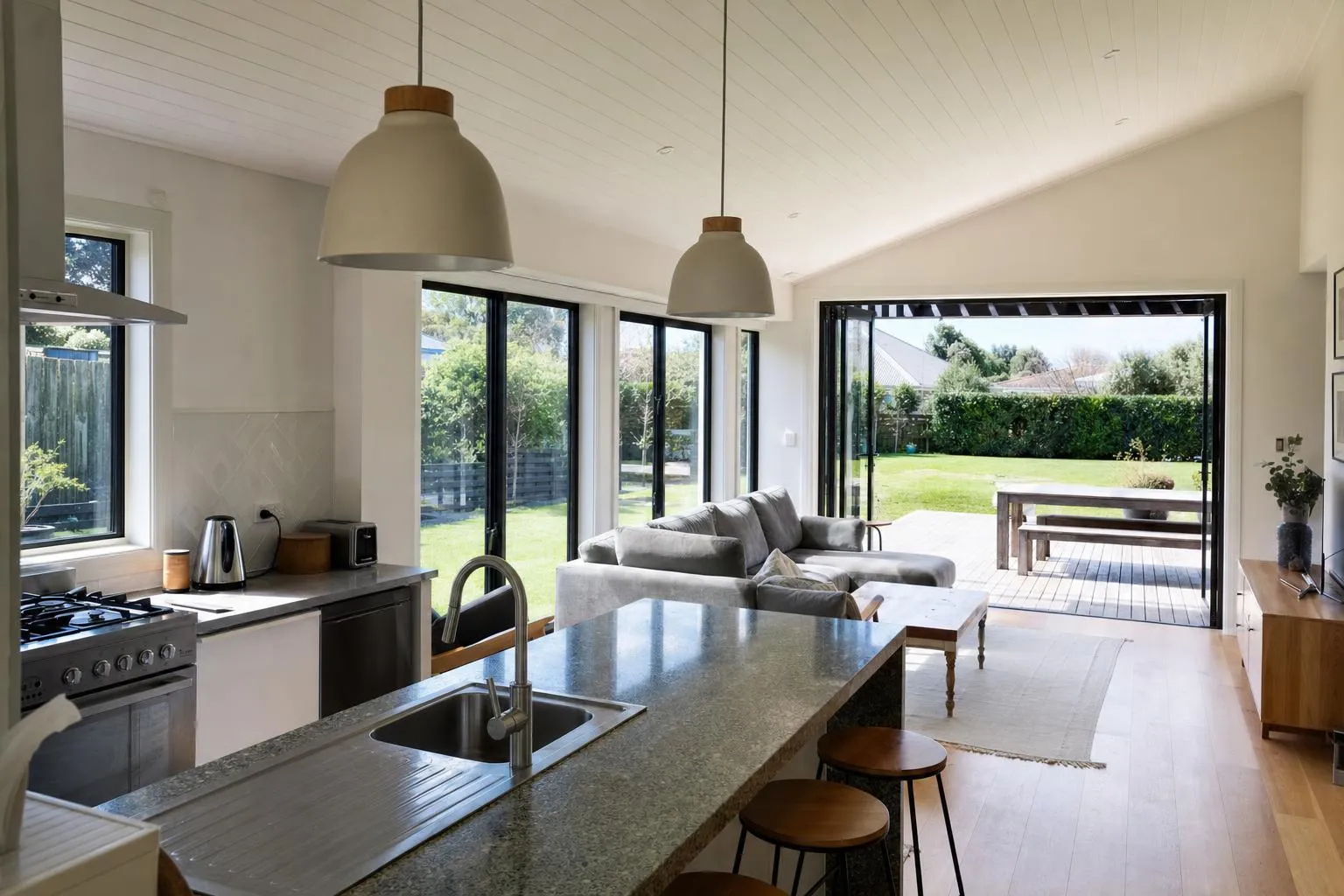 Illustrative: an open-plan kitchen with new slim black aluminium double glazed windows and bifold doors onto a deck