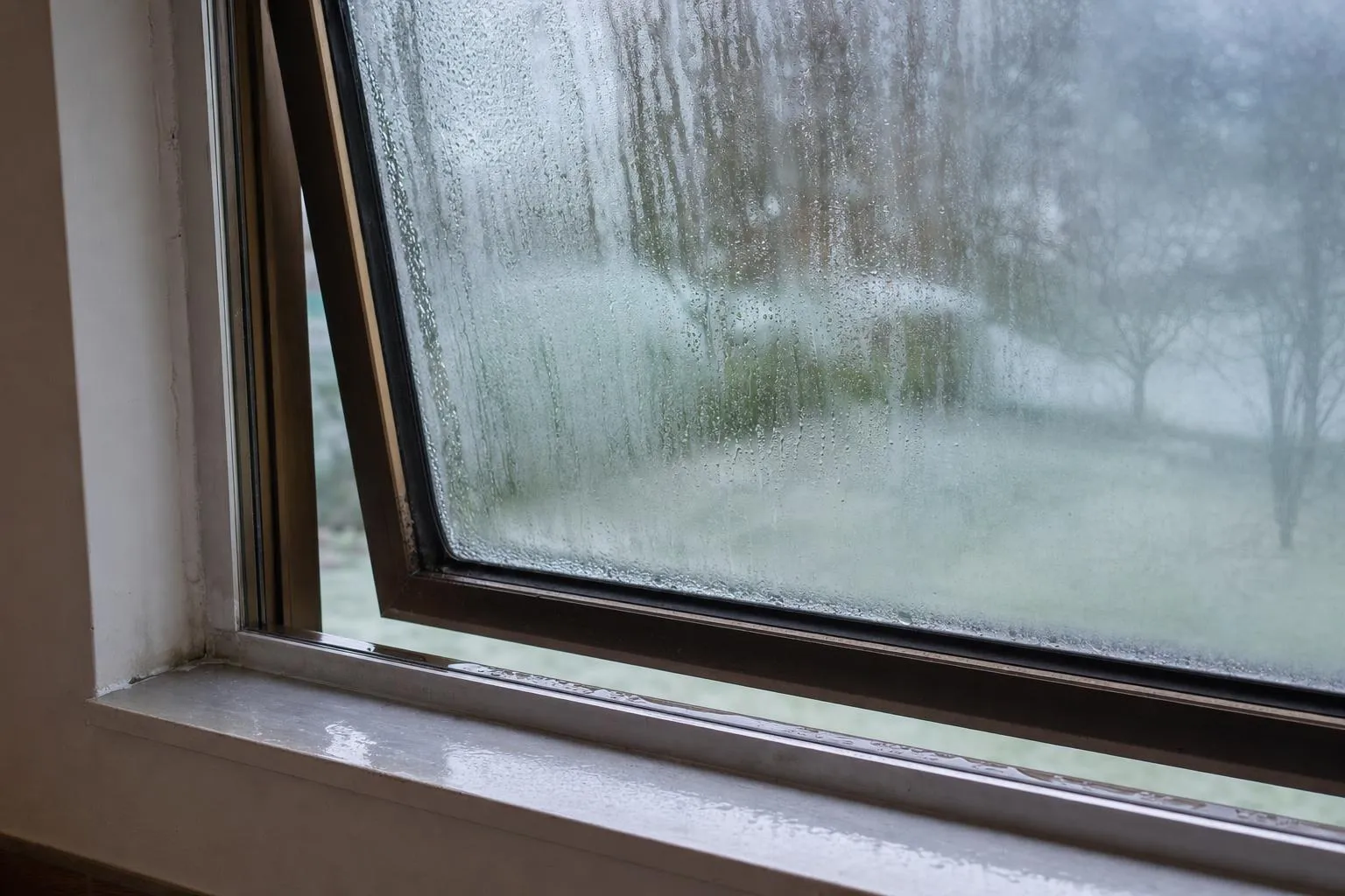 Illustrative: heavy condensation and water pooling on the sill of an old bronze aluminium window