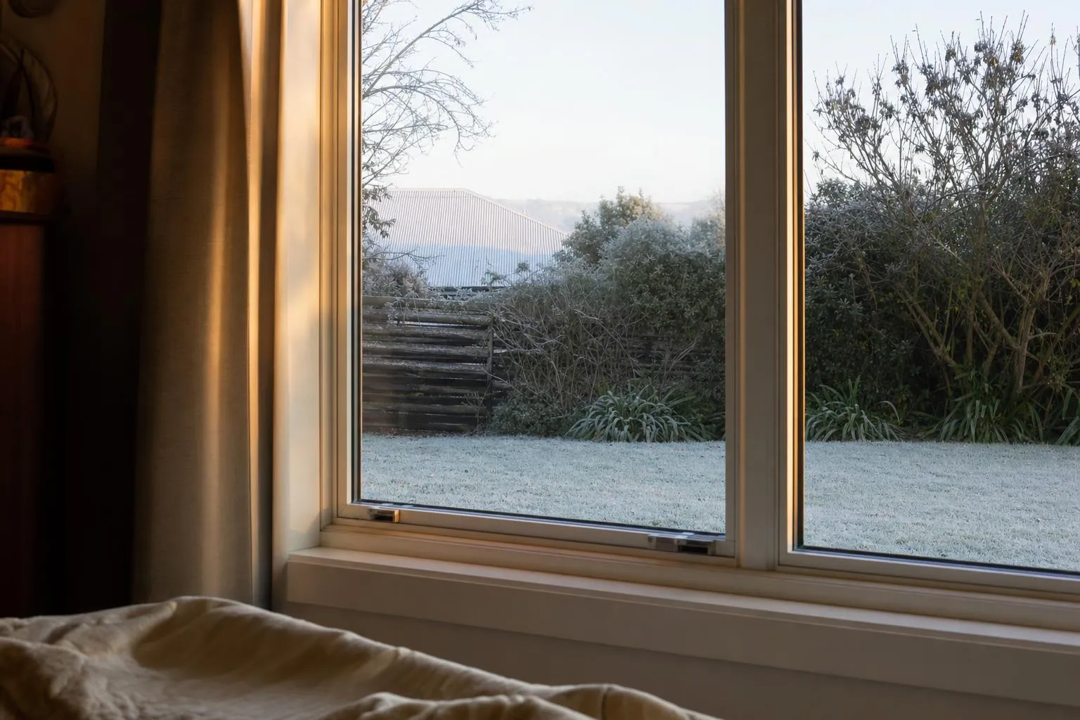 Illustrative: a dry, clear bedroom window with frost on the lawn outside