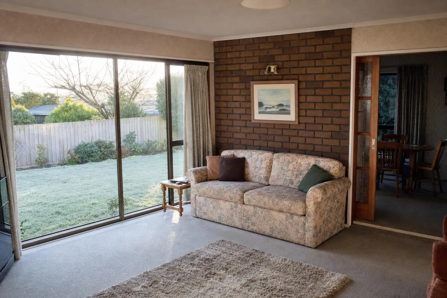 Illustrative: a 1980s lounge with bronze aluminium windows and a ranch slider, frost on the lawn outside